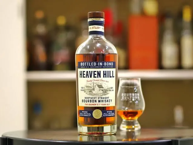 Garrafa de Heaven Hill Bottled-in-Bond de 7 anos ao lado de uma taça de degustação
