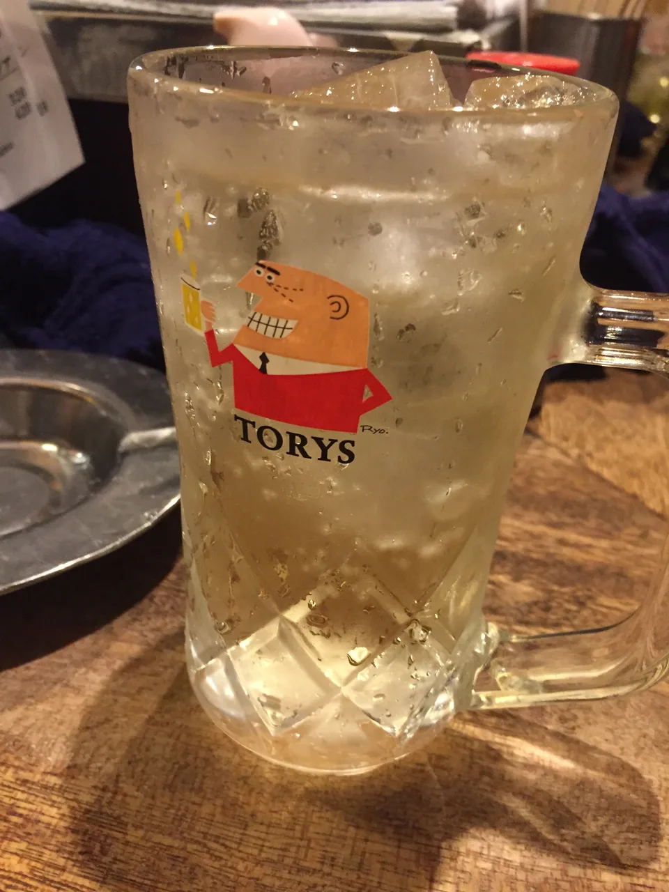 Caneca gelada de highball japonês da marca Torys, cheia de gelo, sobre balcão de bar