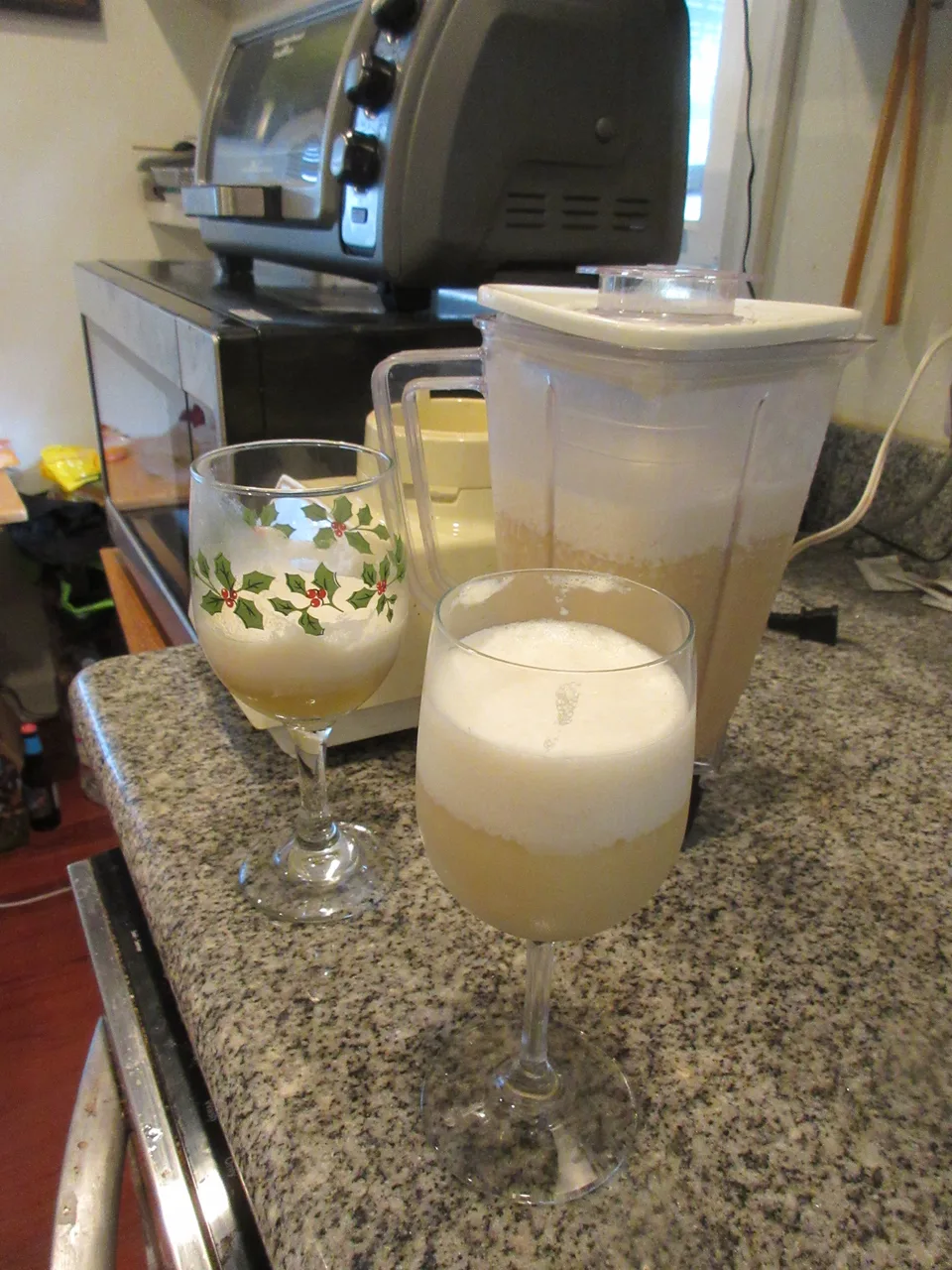 Duas taças de piña colada recém-batidas ao lado do jarro do liquidificador ainda com a mistura