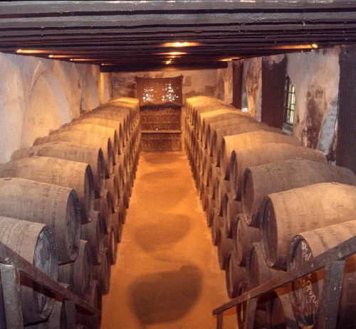 Fileiras de barris de xerez empilhados num sistema solera em Jerez, Espanha